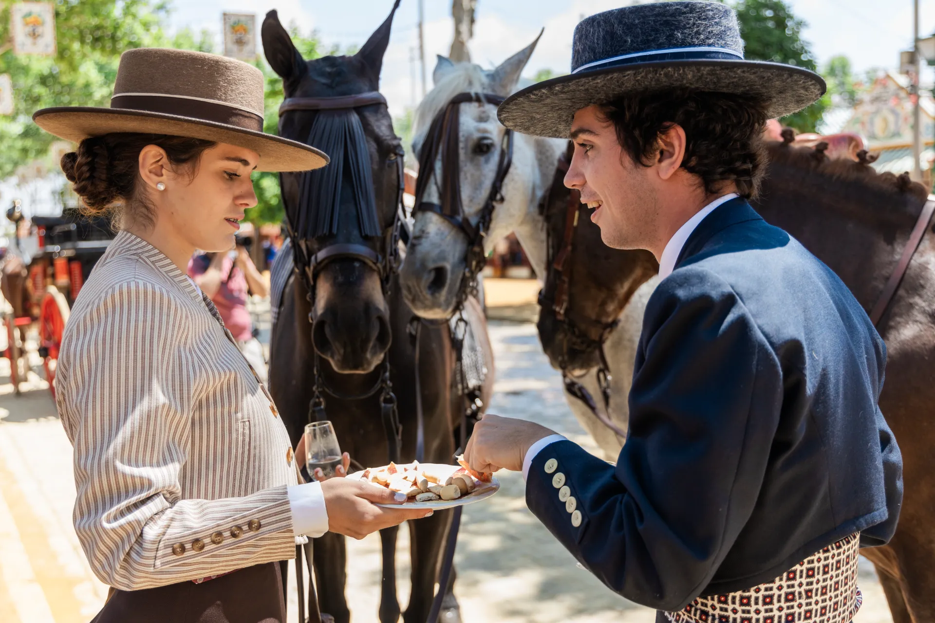 Pareja con trajes típicos comiendo y bebiendo en la Feria del Caballo. Esta imagen se utiliza para ilustrar una entrada sobre la Feria del Caballo de Jerez.