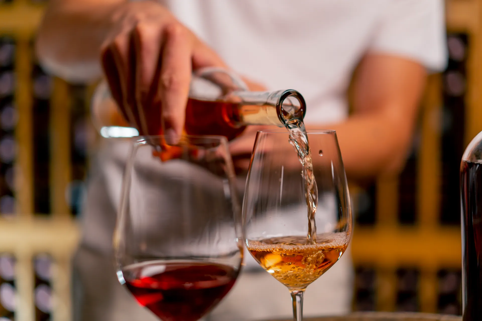 Hombre sirviendo diferents tipos de vino en dos copas. Esta imagen se utiliza para ilustrar una entrada sobre qué es el vino de Jerez.